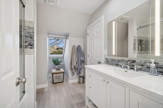 full bath featuring visible vents, baseboards, decorative backsplash, lofted ceiling, and vanity