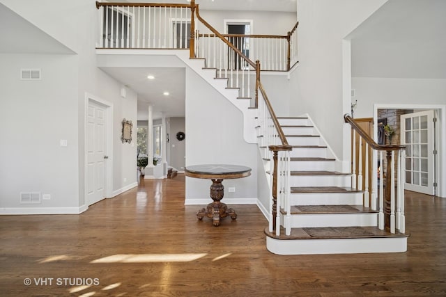 foyer featuring wood finished floors, visible vents, and a towering ceiling