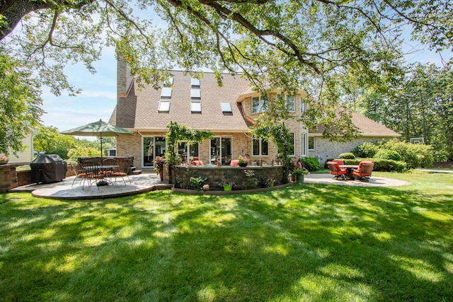 rear view of house with a patio area, a chimney, a shingled roof, and a yard