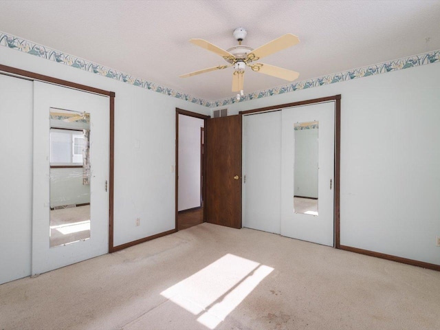 unfurnished bedroom featuring a textured ceiling, baseboards, a ceiling fan, and light colored carpet