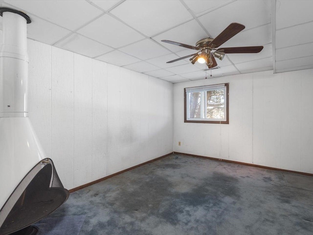 empty room with a ceiling fan, dark colored carpet, and a drop ceiling