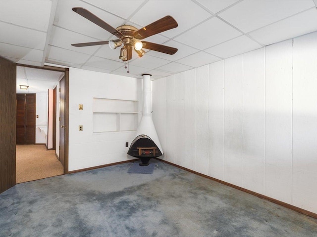 interior space with carpet floors, a paneled ceiling, and a wood stove