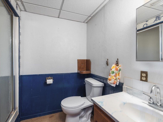 bathroom with toilet, wainscoting, vanity, and a paneled ceiling