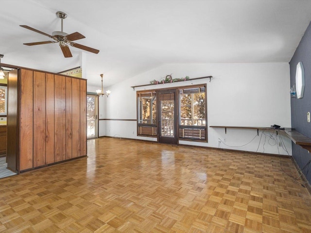 unfurnished living room with vaulted ceiling and ceiling fan with notable chandelier