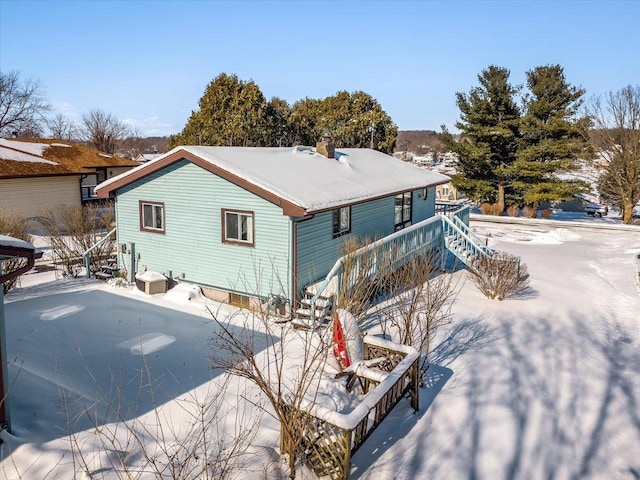 snow covered rear of property with stairs