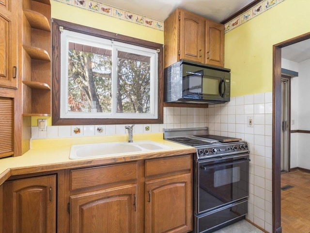 kitchen featuring brown cabinets, black appliances, light countertops, and a sink