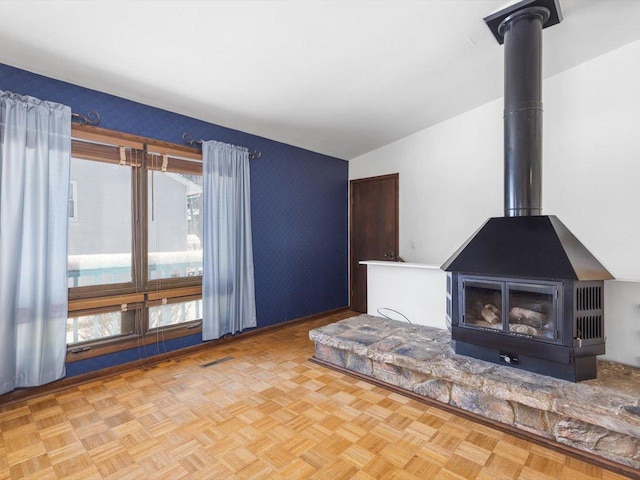 unfurnished living room featuring a wood stove, visible vents, and vaulted ceiling