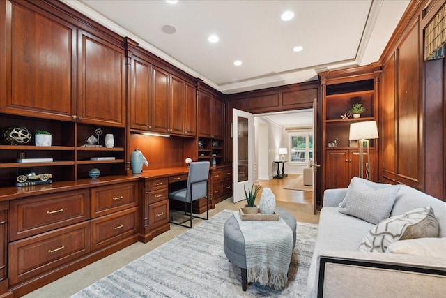 home office featuring built in desk, crown molding, and light colored carpet