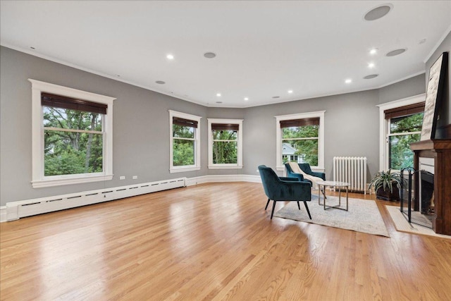 sitting room with a baseboard heating unit, light wood-type flooring, crown molding, and radiator heating unit