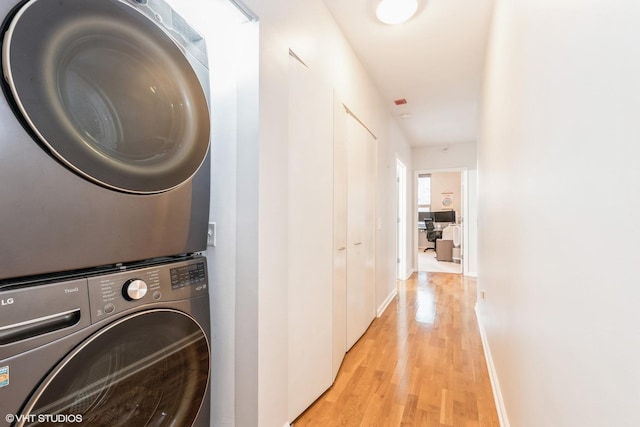 washroom featuring stacked washer / dryer and light hardwood / wood-style floors