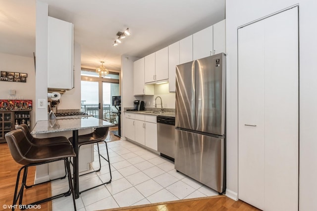 kitchen with a breakfast bar area, stainless steel appliances, white cabinets, and stone countertops