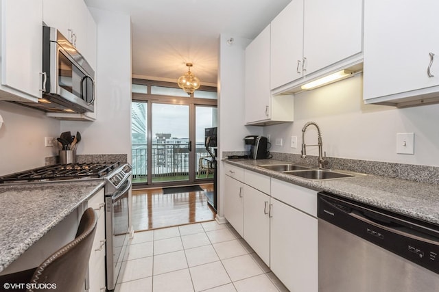 kitchen with light tile patterned flooring, appliances with stainless steel finishes, sink, and white cabinets