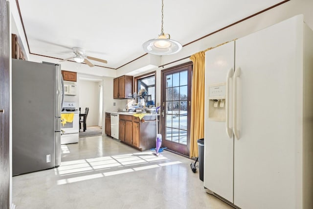 kitchen with pendant lighting, light countertops, brown cabinetry, ceiling fan, and white appliances