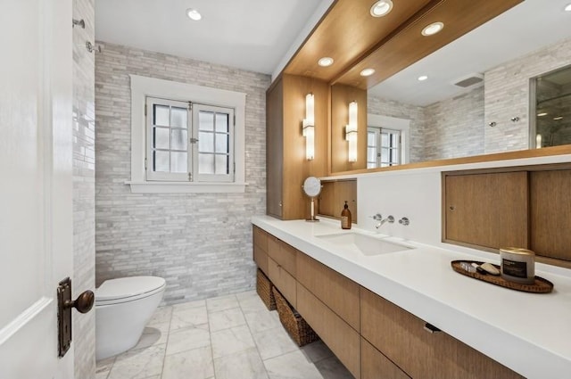 bathroom featuring vanity, tile walls, and toilet