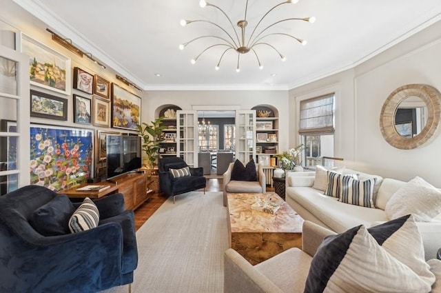 living room featuring crown molding, hardwood / wood-style flooring, built in shelves, and a notable chandelier