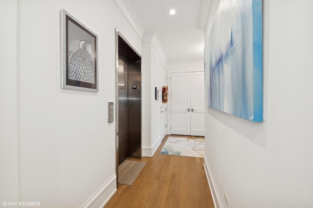 corridor with elevator and light wood-type flooring