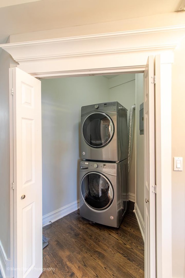 laundry room with stacked washer / drying machine and dark hardwood / wood-style flooring