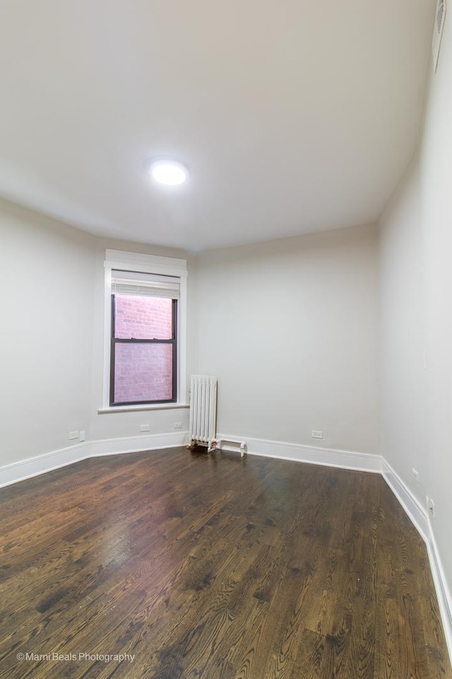 empty room with radiator and dark wood-type flooring