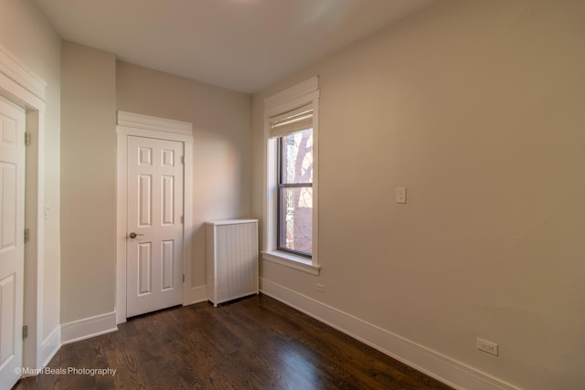 unfurnished bedroom with dark hardwood / wood-style flooring and radiator