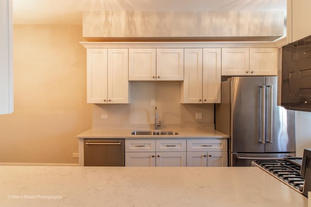 kitchen with light stone countertops, appliances with stainless steel finishes, sink, and white cabinets