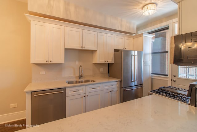 kitchen with white cabinetry, sink, light stone counters, and stainless steel appliances