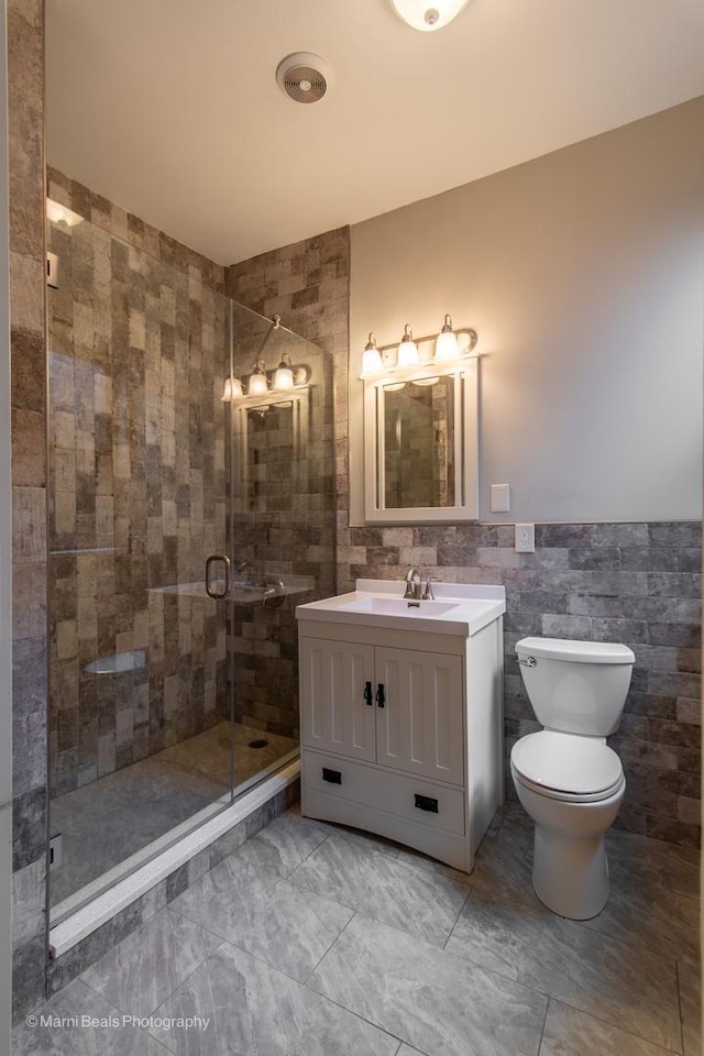 bathroom with vanity, tile walls, an enclosed shower, and toilet