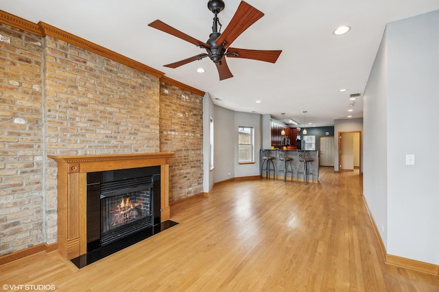 unfurnished living room featuring light wood-type flooring, ceiling fan, and a fireplace