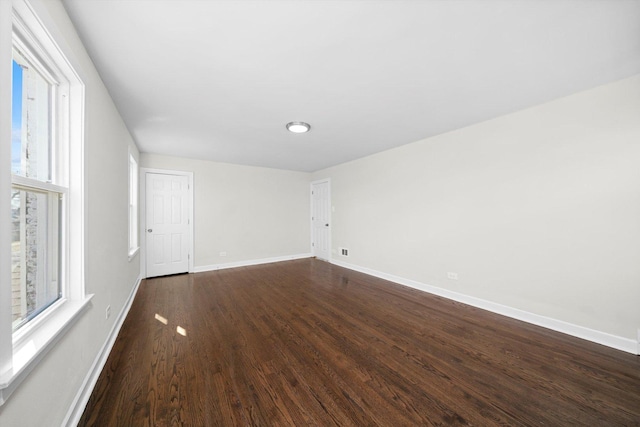 unfurnished room featuring dark wood-type flooring and baseboards