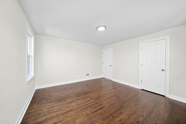 unfurnished room with baseboards and dark wood-style floors