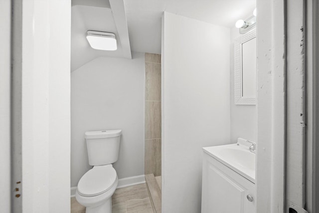 full bath featuring vanity, toilet, baseboards, and a tile shower