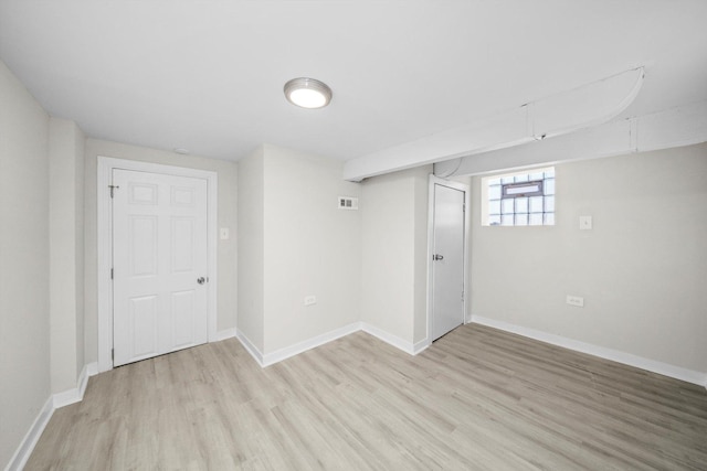 below grade area with light wood-type flooring, baseboards, and visible vents