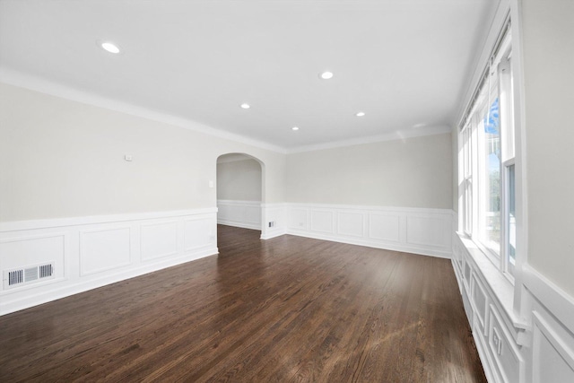 spare room with visible vents, a wainscoted wall, dark wood-style floors, recessed lighting, and arched walkways