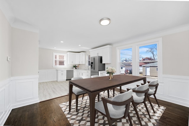 dining space featuring a decorative wall, recessed lighting, dark wood-style floors, and a wainscoted wall