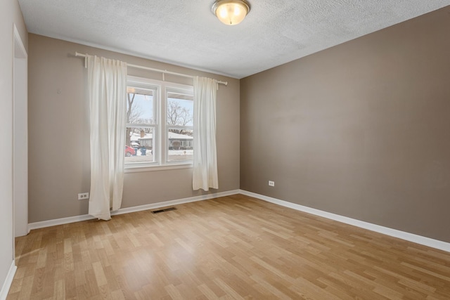 empty room featuring light hardwood / wood-style flooring and a textured ceiling