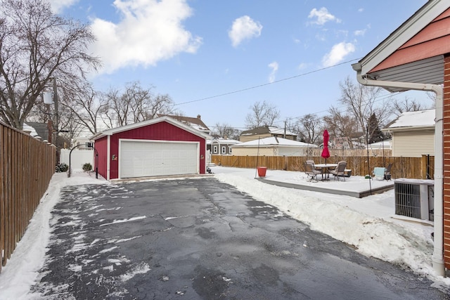 yard layered in snow with an outbuilding, central AC unit, and a garage