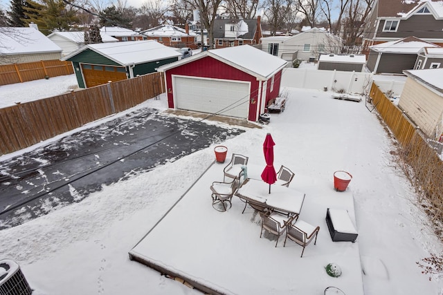 yard layered in snow featuring an outbuilding and a garage