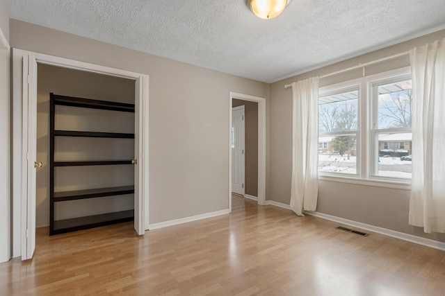 unfurnished bedroom with light hardwood / wood-style floors, a closet, and a textured ceiling