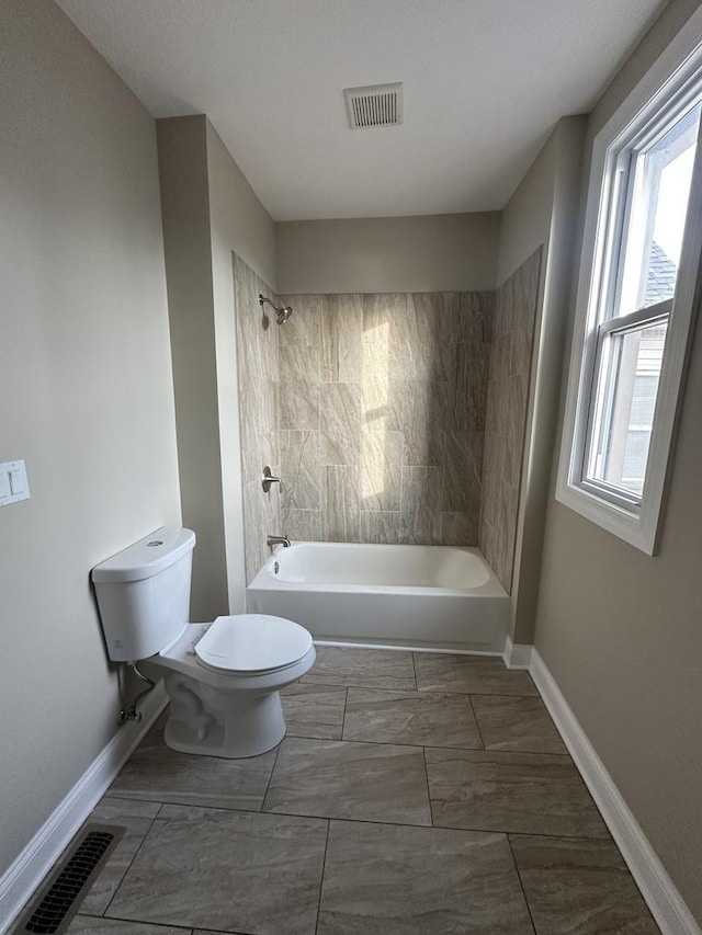 bathroom with toilet, tiled shower / bath combo, and a wealth of natural light