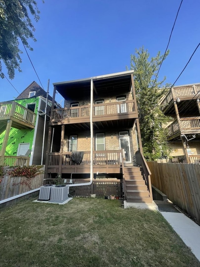 rear view of property with a balcony, a yard, and central AC unit