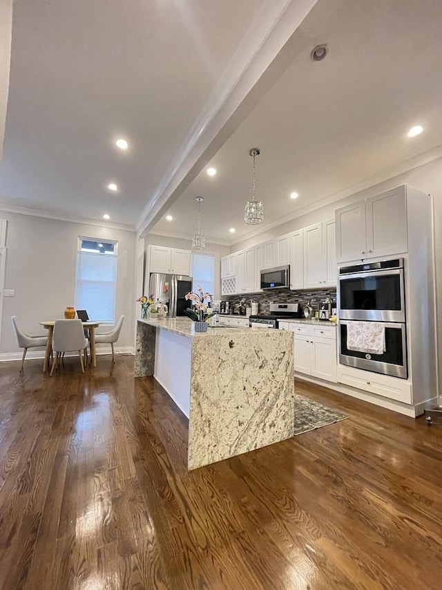 kitchen featuring pendant lighting, appliances with stainless steel finishes, light stone counters, white cabinets, and dark hardwood / wood-style flooring