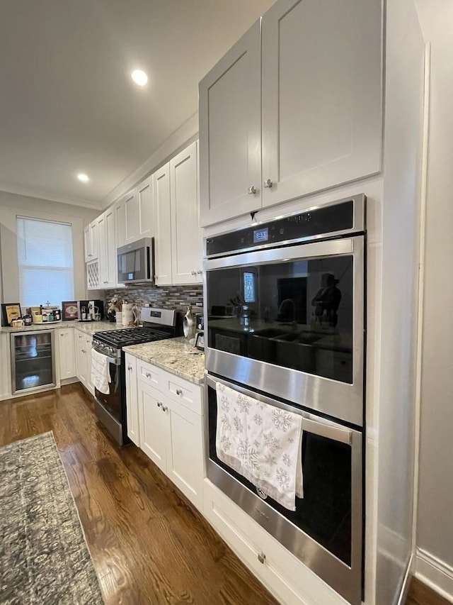 kitchen with stainless steel appliances, light stone counters, wine cooler, white cabinets, and dark hardwood / wood-style flooring