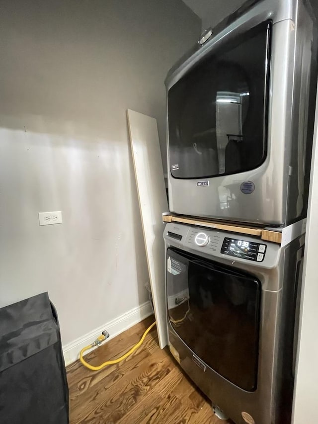 laundry area featuring stacked washer and clothes dryer and hardwood / wood-style floors