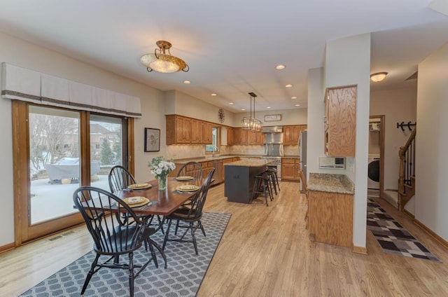 dining area featuring light wood-type flooring, washer / dryer, and sink