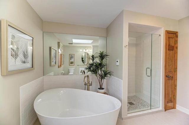 bathroom featuring plus walk in shower, a skylight, and tile walls