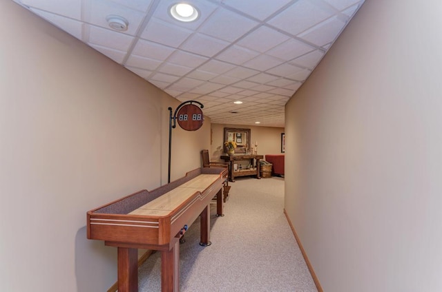 hallway with carpet floors and a paneled ceiling