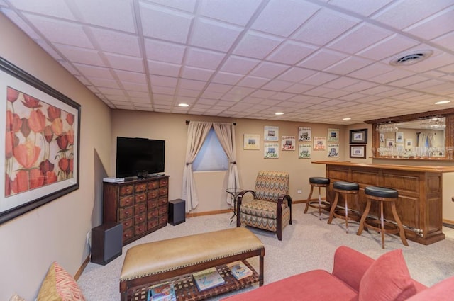 carpeted living room featuring a paneled ceiling and bar area