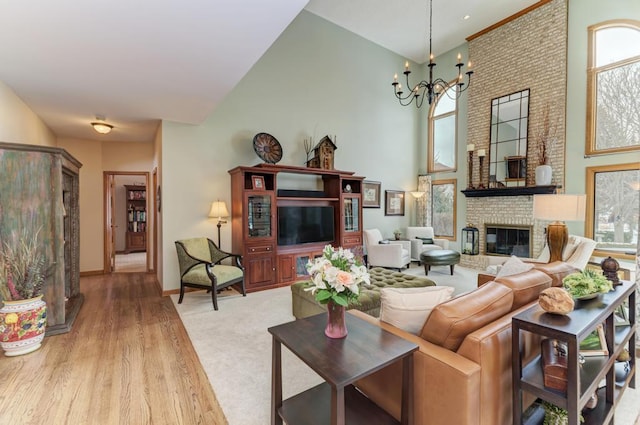 living room with a high ceiling, light wood-type flooring, a chandelier, and a fireplace