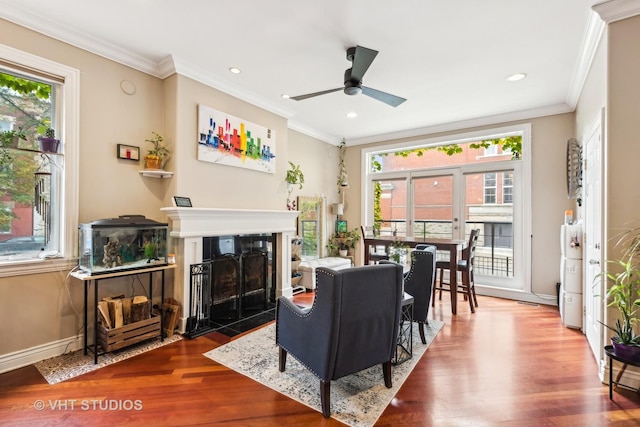 living room featuring wood-type flooring, ornamental molding, and ceiling fan