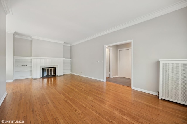 unfurnished living room with light wood-style flooring, a fireplace with flush hearth, baseboards, radiator heating unit, and crown molding