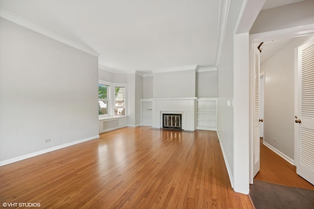 unfurnished living room featuring a fireplace with flush hearth, crown molding, baseboards, and wood finished floors